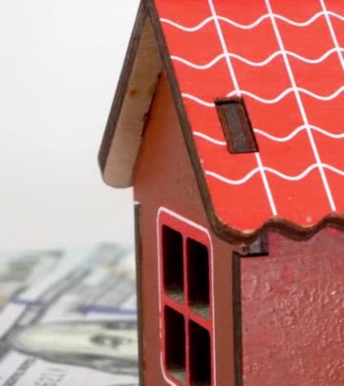 小型家庭房屋的模型站在美元钞票的背景上，并缓慢旋转。