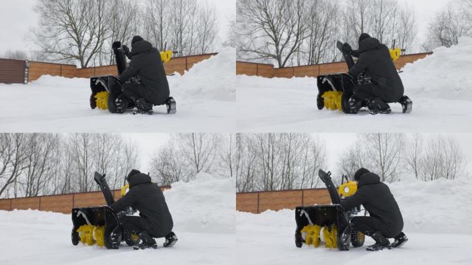 在后院用扫雪机扫雪之前，男人会调整吹雪机。安装扫雪机。慢动作