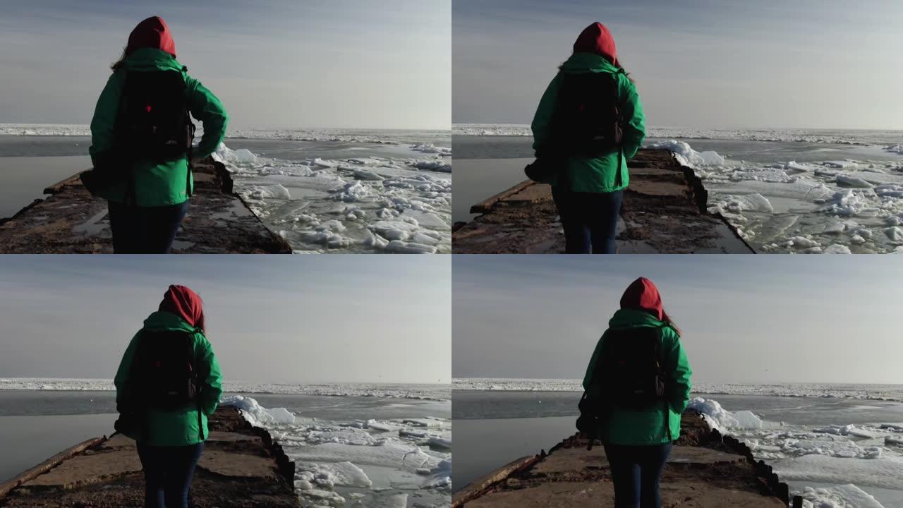 女孩在日落时走在冰冻的海边。冬。亚速海。