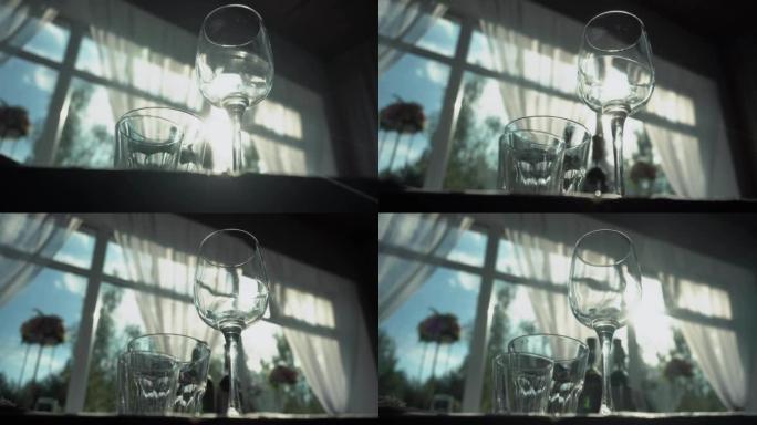 一杯酒和玻璃玻璃杯站在桌子上，背景是透过窗户照耀的阳光。节日，庆祝活动的餐桌