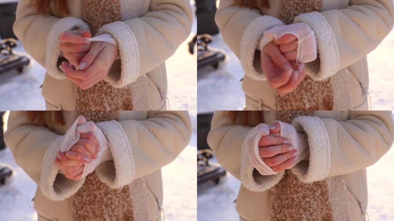 在寒冷的冬日里，冷冻的无法辨认的女人揉手试图热身站在户外的特写镜头。