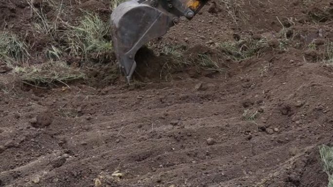 挖掘机铲斗铲去除了顶层的土壤并将其清理起来