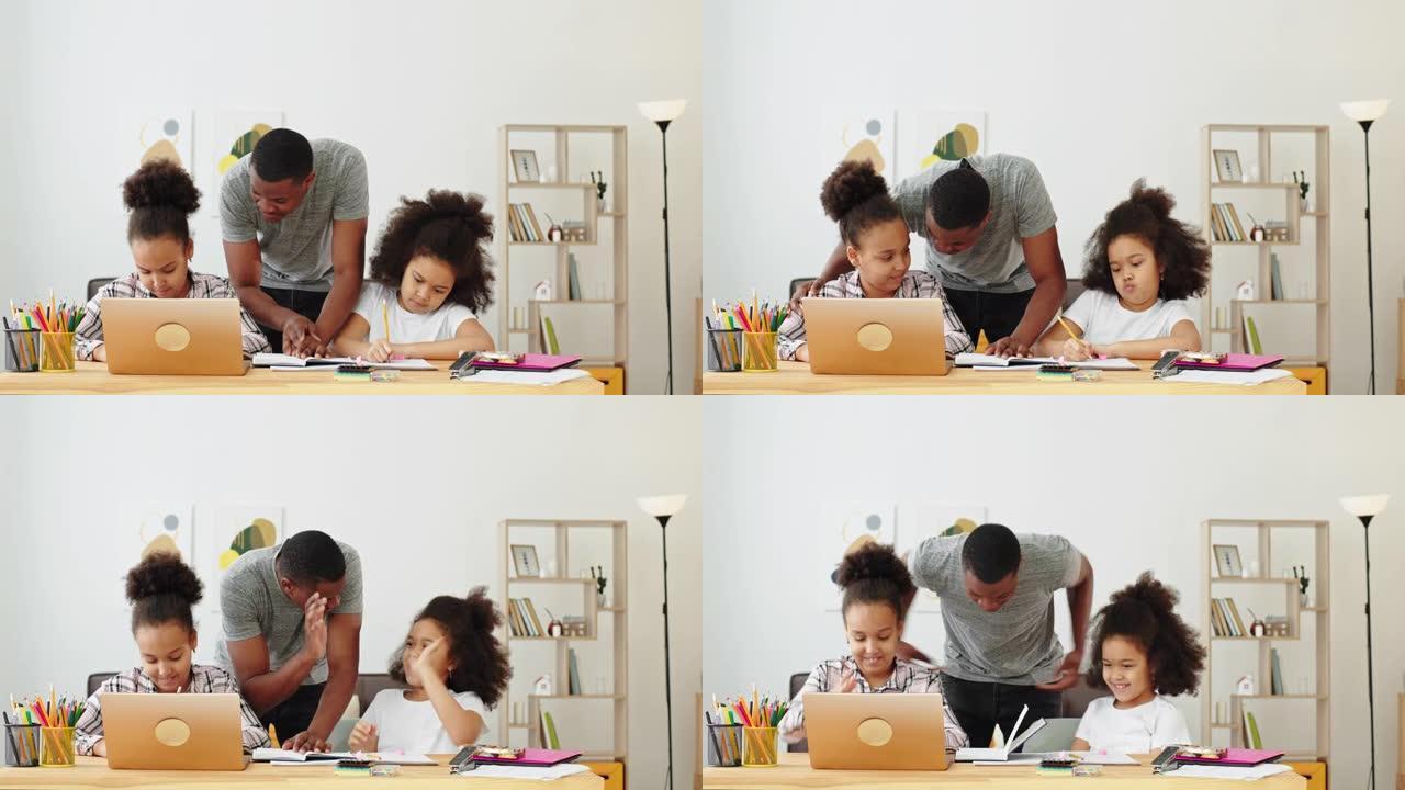 学习在线乐趣微笑积极情绪黑人家庭非洲裔美国爸爸在家上课，他的女儿坐在桌子和笔记本电脑旁