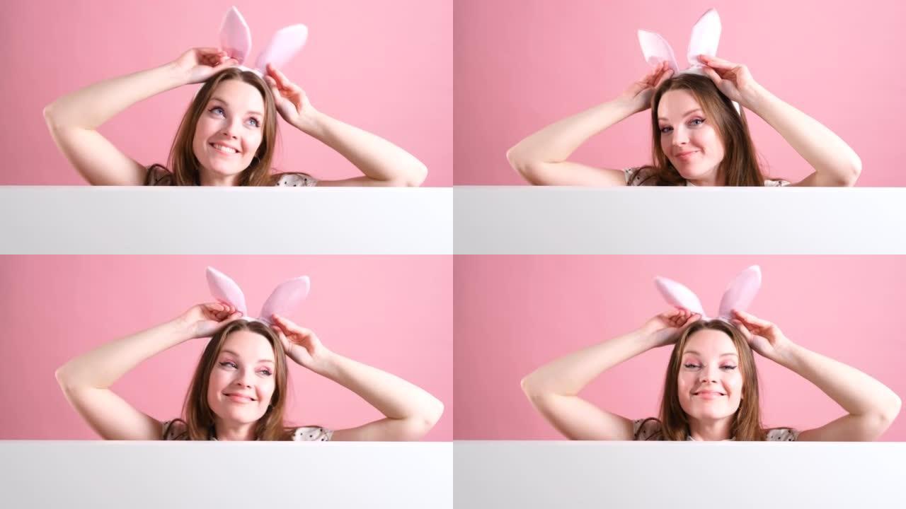 美丽的女人戴着兔子耳朵在粉红色背景上跳舞。
