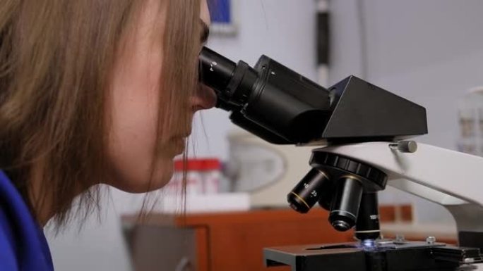 一个穿着实验服的女人的特写镜头正准备开始显微镜研究