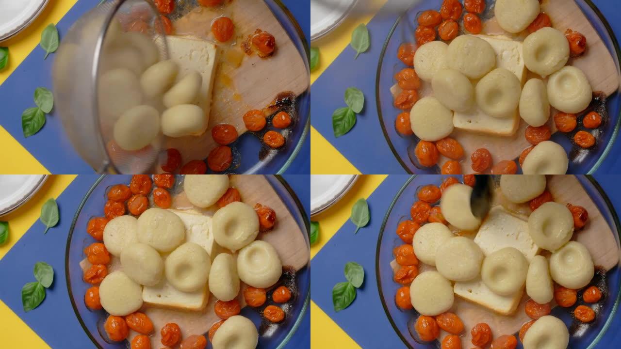 垂直桌面视频: 厨师将煮熟的土豆饺子添加到烤西红柿和羊乳酪中
