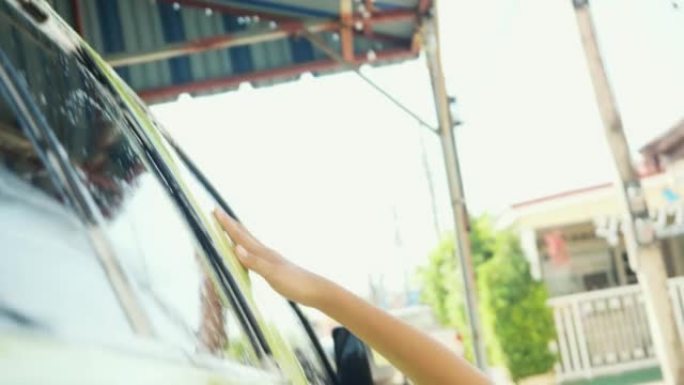 亚洲女孩在家洗绿色汽车和挡风玻璃，生活方式概念。