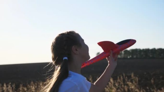 无忧无虑的小孩手持玩具飞机在背景下在阳光下慢跑。快乐的小女孩在乡下坐飞机跑步。快乐的孩子在大自然中玩