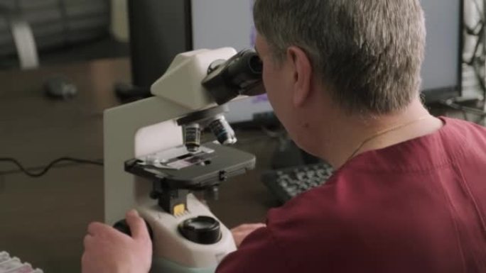 男性微生物学家，医务人员通过显微镜观察血液样本，并在实验室进行分析。实验室助理使用现代显微镜进行生物