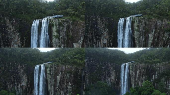 揭示一个受欢迎的旅游了望点，旁边是一个雄伟的瀑布，喷涌在五颜六色的悬崖面上。移动无人机视图