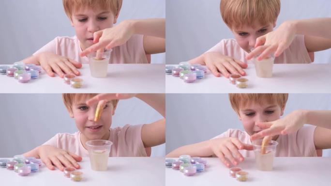 孩子的手是特写的。一个小学年龄的孩子从罐子里取出粘液。不同颜色的切片。孩子把玩具放在他面前的桌子上。