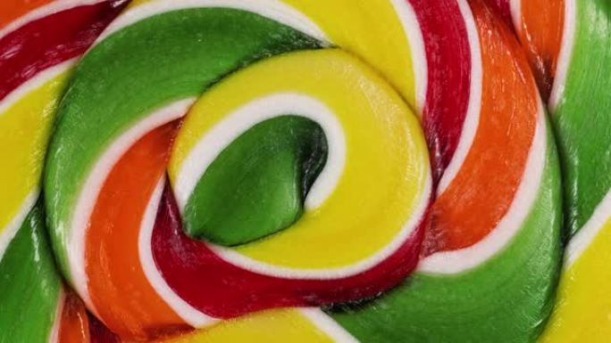 螺旋水果棒棒糖旋转的极端宏观视图。焦糖棒棒糖。儿童糖果。童年概念。