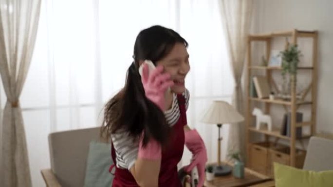 喜出望外的亚洲家庭主妇在家里打扫房子时接到手机通知后，兴奋地尖叫着获奖