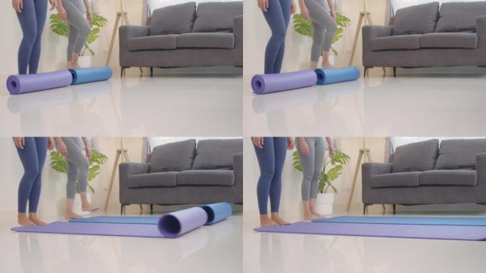 两名亚洲妇女在客厅里散布瑜伽垫进行放松锻炼。用脚铺垫子。热爱健康的人。健康的生活方式理念。