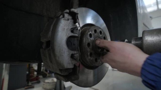 汽车修理工在维修服务站更换举升汽车的车轮制动蹄