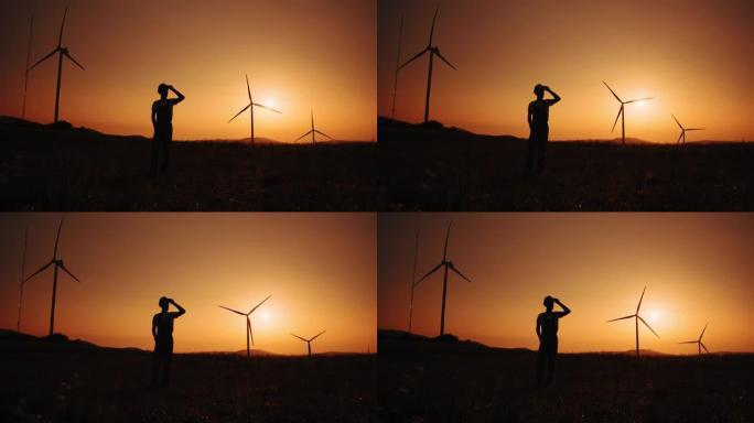 剪影非裔美国人在夏季日落时站在大风车上。环境污染的概念，替代能源的新技术。风车的背景