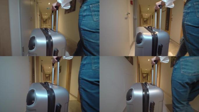 走在酒店走廊上的女人的后视。把她的行李放在她身后