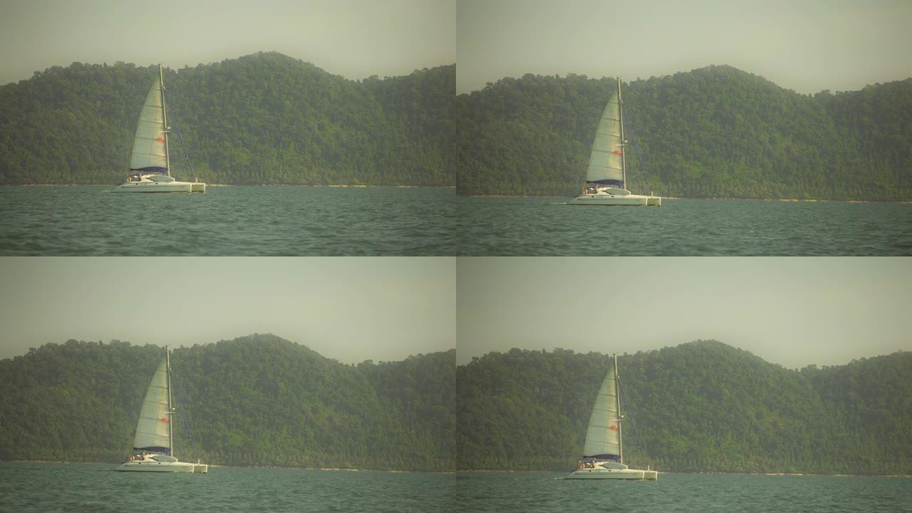 复古棕褐色温暖的景色。优美的帆船的慢动作镜头在蓝色的绿松石平静的海水中滑行。热带暑假。在开阔的海洋上