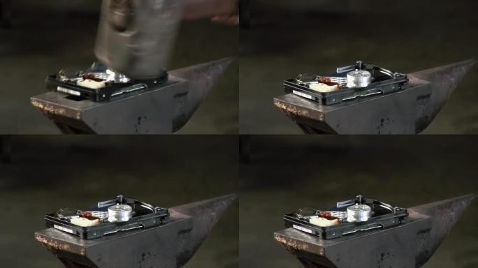 一名男子在铁砧上用一把大锤砸碎硬盘。慢动作特写有声音