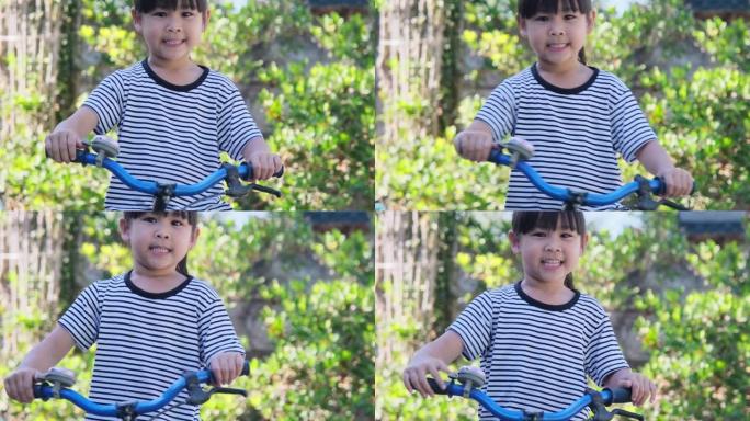 开朗的微笑女孩在自行车车把上敲响自行车铃，准备在公园里骑自行车。