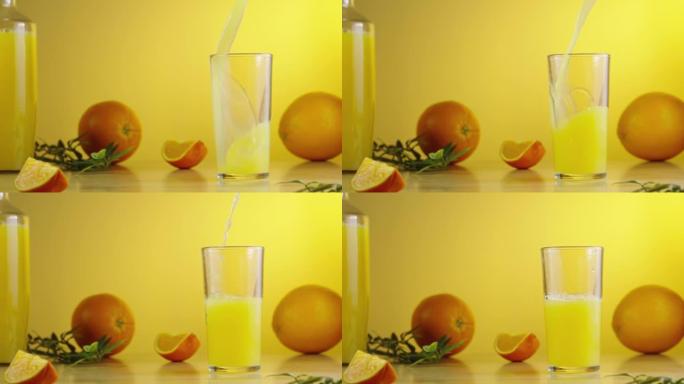 将鲜榨的甜橙汁倒入玻璃杯中。早上早餐的黄色厨房背景。玻璃中的异国天然柑橘花蜜。饮食健康热带饮料。慢动