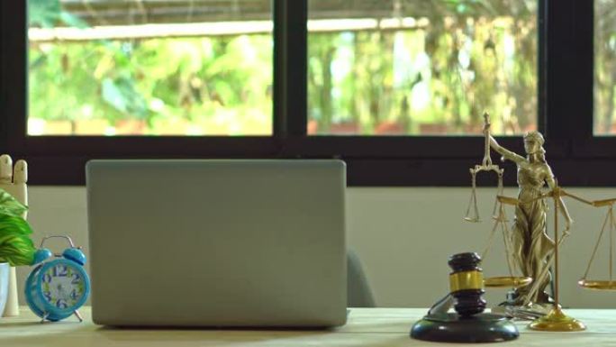 在律师的办公室里，旁边放着法官的锤子和装有装饰品的笔记本电脑。