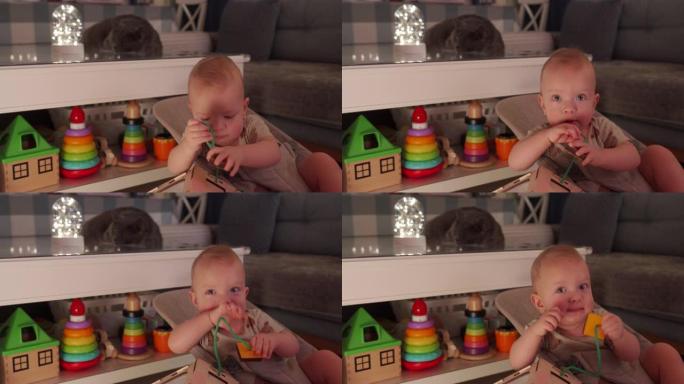 男婴在家玩木制忙碌的房子蒙特梭利教育玩具。儿童忙板。