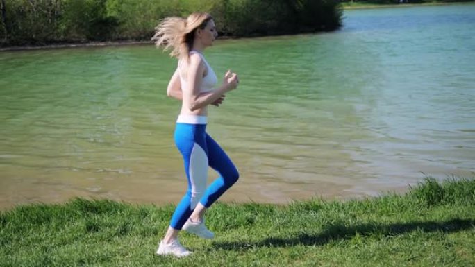 夏天，阳光明媚的日子里，一名运动女子在公园的湖边呼吸新鲜空气