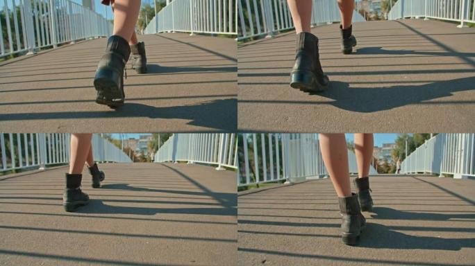 一个女人的腿沿着城市公园的桥走。秋季夏季