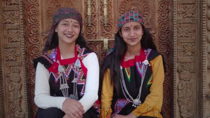 两个穿着传统服装的微笑的年轻印度农村妇女看着相机