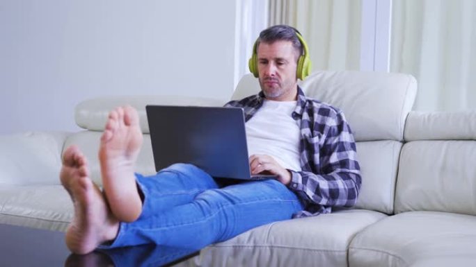 男人用笔记本电脑和耳机听音乐