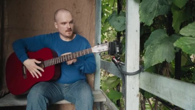 男子在郊区农场的门廊上主持在线原声吉他课程