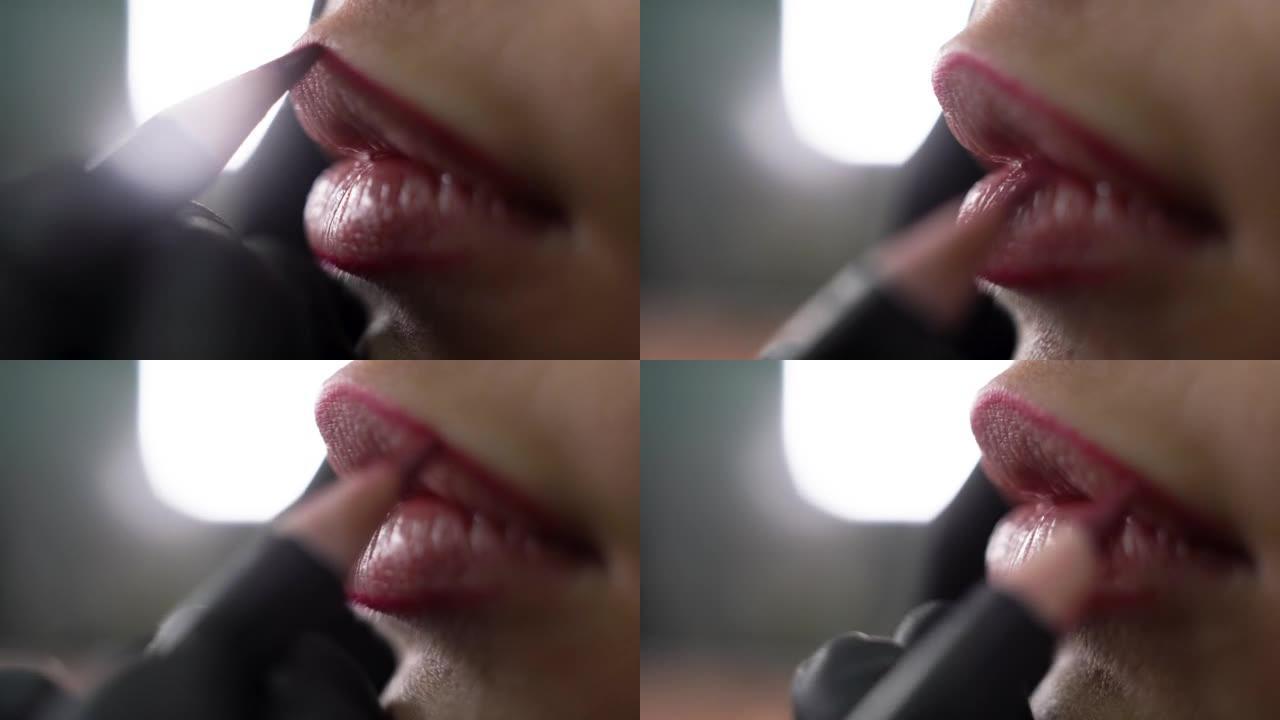 永久的嘴唇纹身程序，主人在黑色手套用铅笔勾勒出嘴唇的轮廓。这个女孩使性感丰满的嘴唇轮廓。