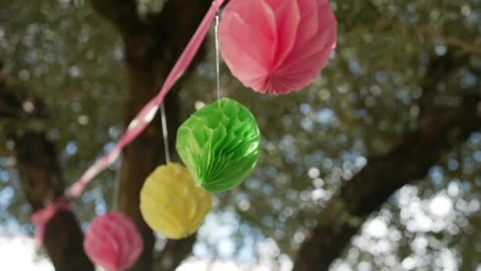 彩带挂在树上纸质纸花彩球随风摇动休闲时光