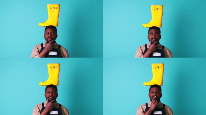 尼日利亚园丁男子在蓝色工作室展示黄色橡胶鞋，为秋季春季做好准备