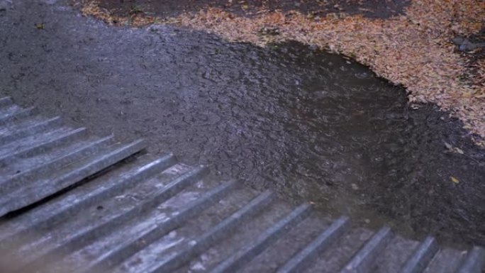 雨滴向下流下，在倾盆大雨中从屋顶掉落在水坑中。4K