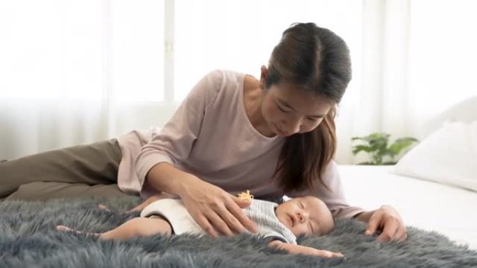 4K 50fps，新生儿，2个月大的亚洲宝宝在地毯上睡觉。他妈妈哄他温暖地睡在你身边