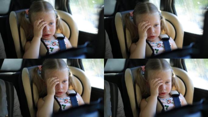 两岁的女孩坐在儿童汽车座椅上的汽车上。哭泣和非常沮丧。