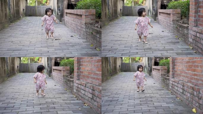 穿着和服的好奇的亚洲女性蹒跚学步的孩子正停下来看着远处，一边快乐地奔向镜头