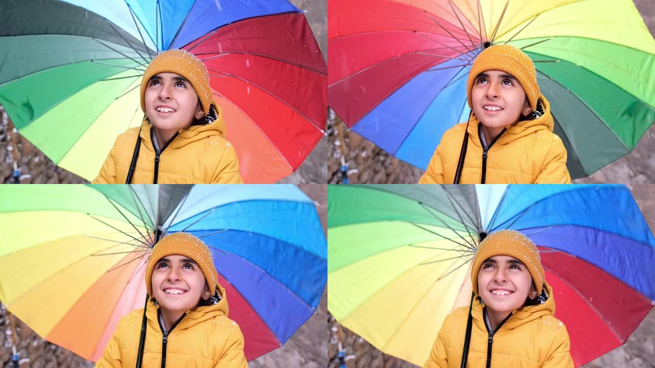 彩虹色雨伞下雪时，小女孩感到幸福