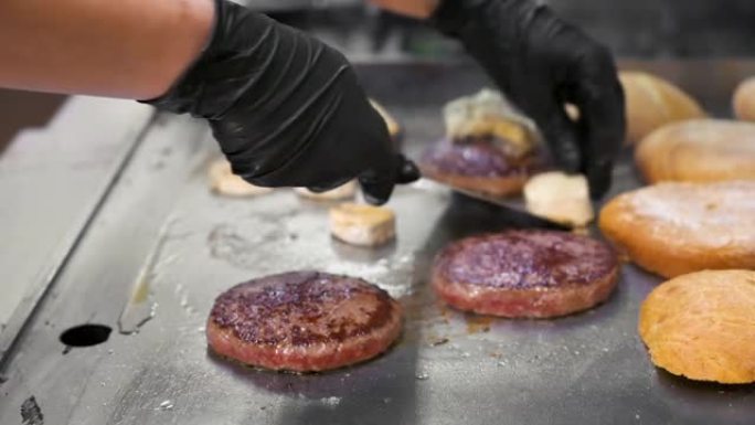 在汉堡店的煎锅上翻转汉堡肉饼和加热面包的特写镜头。高质量全高清镜头