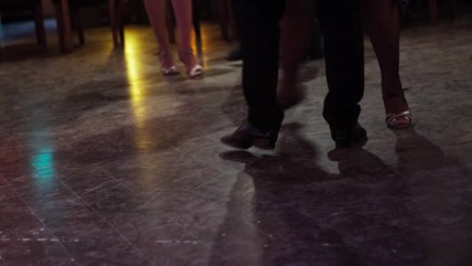 特写舞者的腿在黑暗照明的大厅里表演探戈。