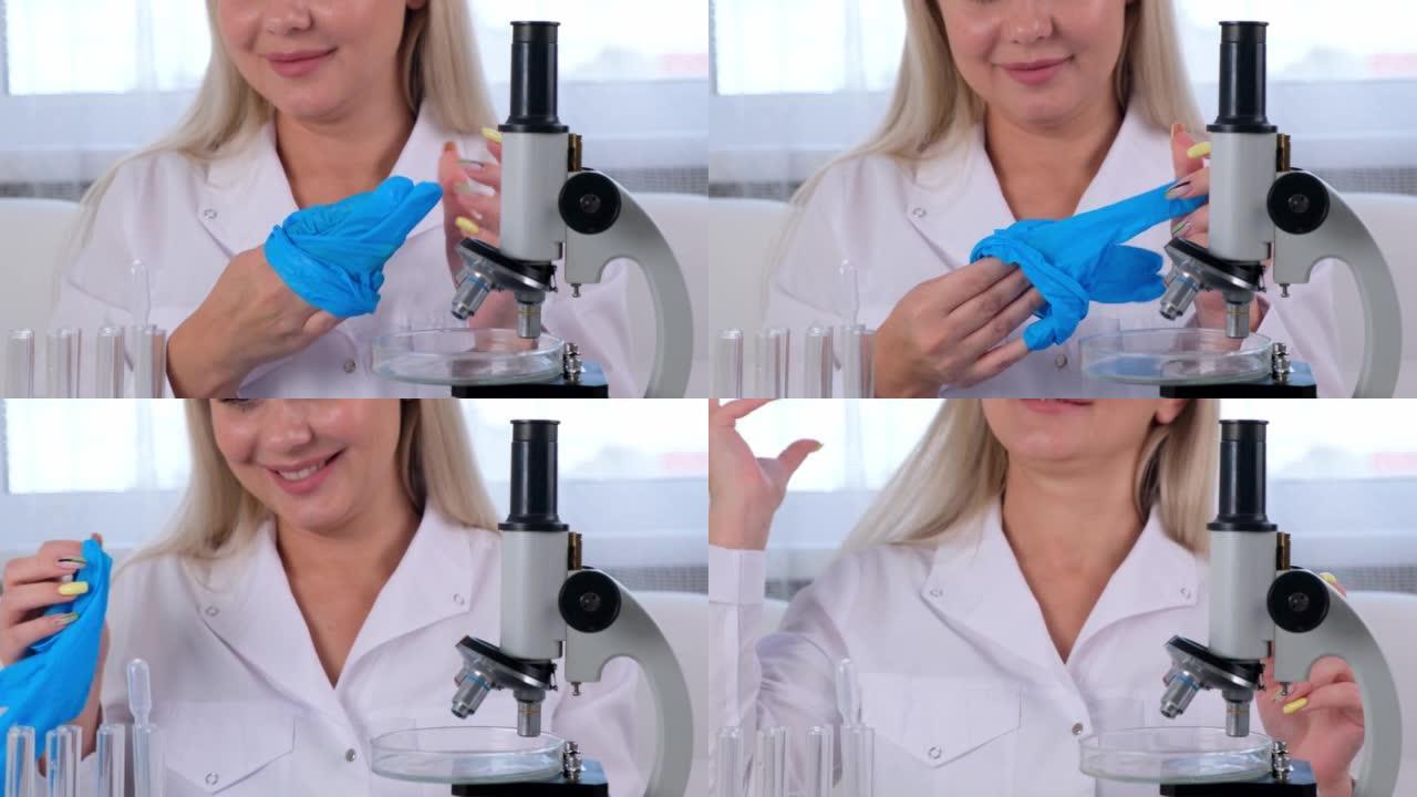 女科学家实验室助理完成了在显微镜下研究试管中微生物的工作，并脱下了防护手套。一个女人在显微镜下的实验