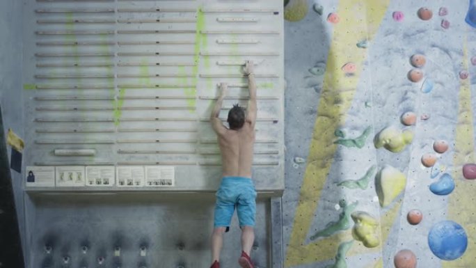 一个运动的人爬上指板来模拟攀岩。积极的生活方式，极限运动抱石。手指训练用攀岩设备