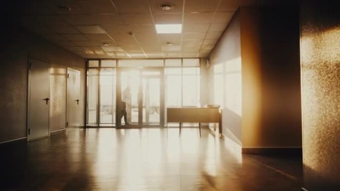 男人在明亮的阳光下在大厅里走路和打电话的剪影