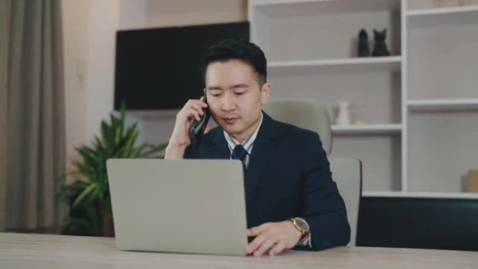 年轻的亚洲商人在手机和笔记本电脑上聊天。