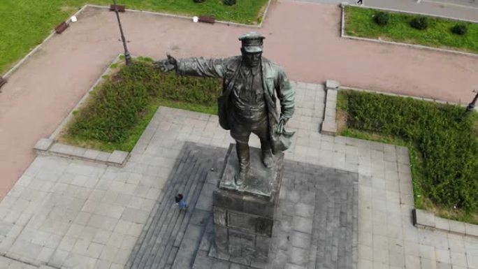 列宁纪念碑在一个有鸽子的基座上。戴着帽子伸出手的男人