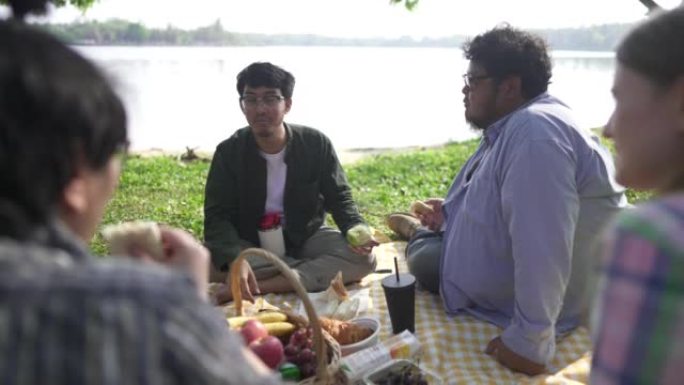 年轻人在湖岸和朋友野餐。