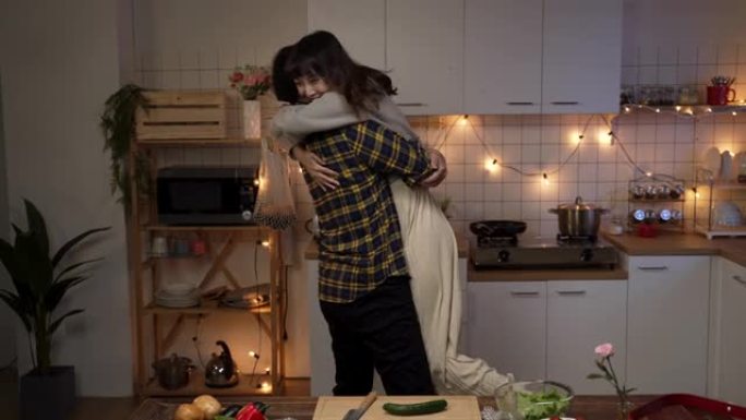 亚洲男友在家里的情人节之夜约会中拥抱并举起他快乐的女友。男人在考虑并同意满足女人的愿望时揉手
