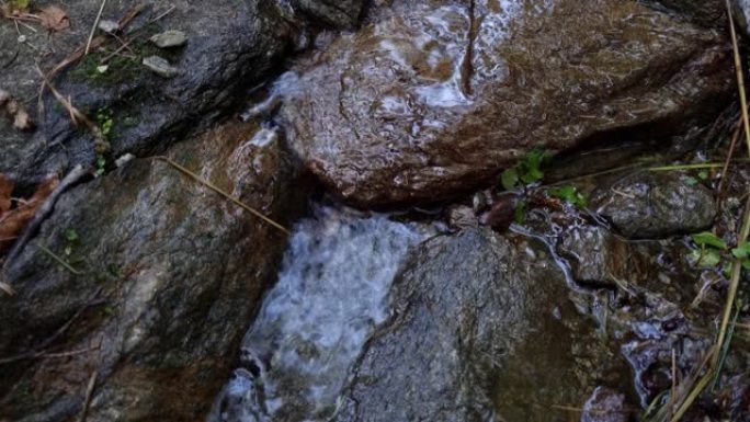 一条小溪流过岩石。春天来了，雪正在融化。冬季后自然的复兴